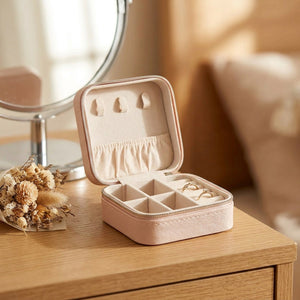 Boîte à bijoux rose ouverte sur une coiffeuse avec miroir et fleurs séchées