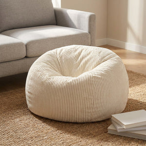 Pouf blanc en velours côtelé près d'un canapé gris dans un salon