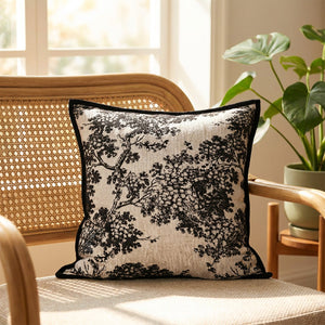 Housse de coussin toile de Jouy sur un fauteuil en rotin près d'une fenêtre