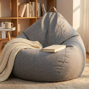 Pouf poire gris chiné avec un plaid tricoté et un livre dans un coin lecture