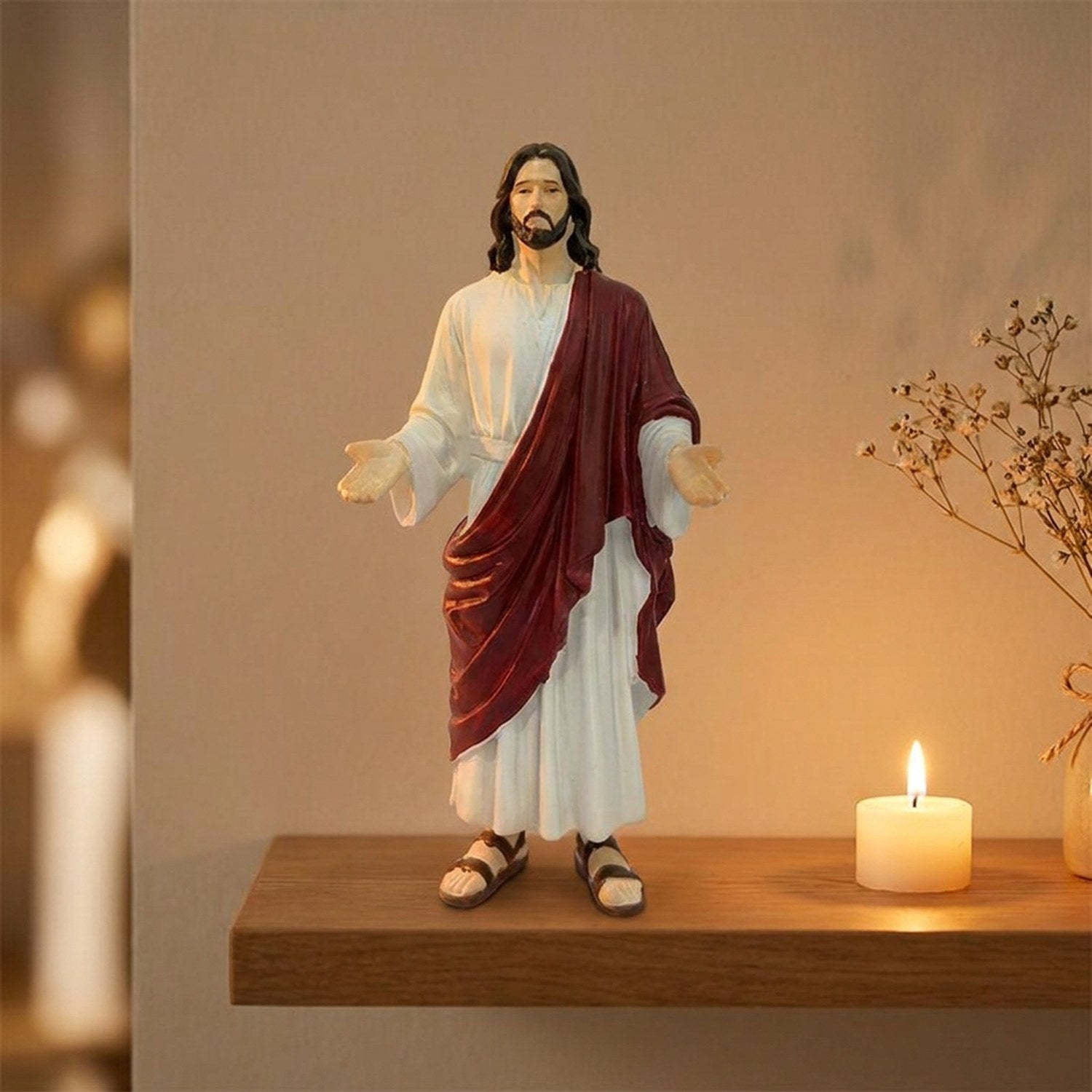 Statue de Jésus-Christ en résine sur une étagère en bois éclairée par une bougie