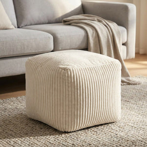 Tabouret pouf blanc utilisé comme repose pieds devant un canapé