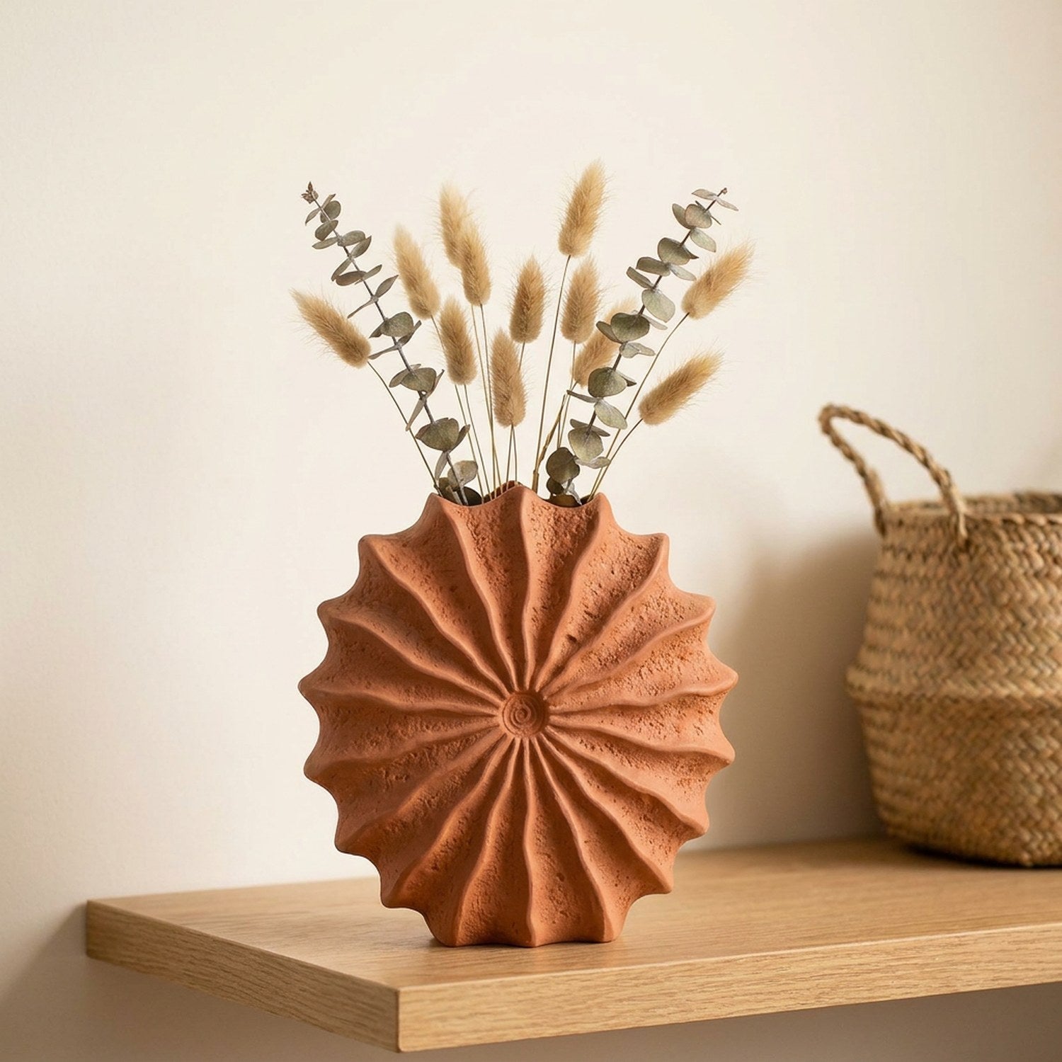 Vase coquillage terracotta avec eucalyptus séché sur une étagère en bois