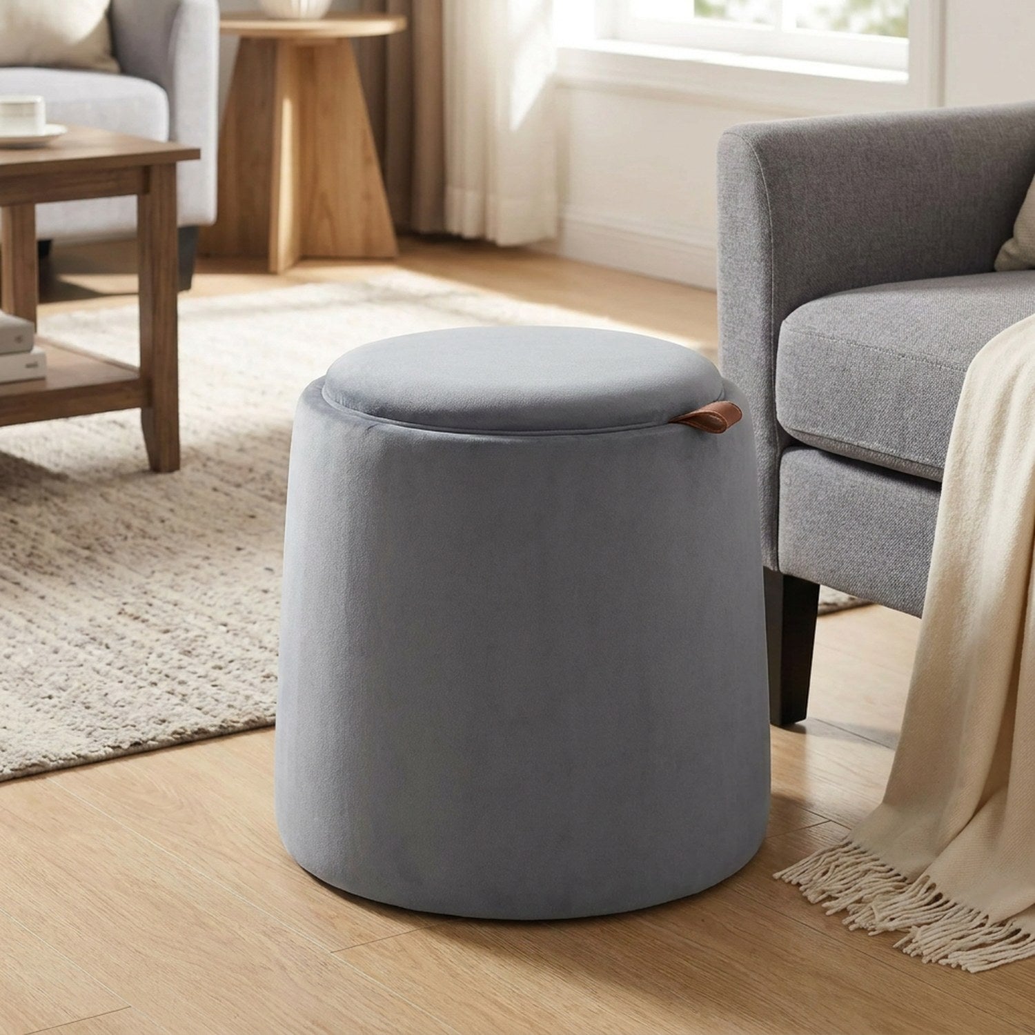 Pouf coffre de rangement gris dans un salon près d'un fauteuil et d'une table basse