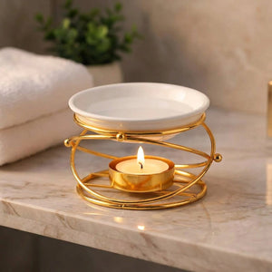 Brûle-parfum doré posé sur une tablette de salle de bain en marbre avec serviettes