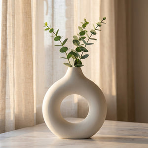 Vase anneau blanc sur une surface en marbre près d'une fenêtre avec des branches d'eucalyptus