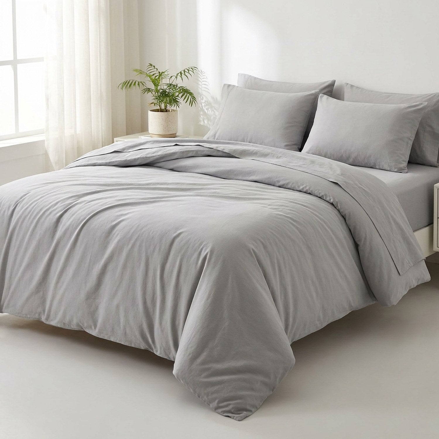 Parure de lit en coton lavé gris clair sur un lit dans une chambre lumineuse et minimaliste