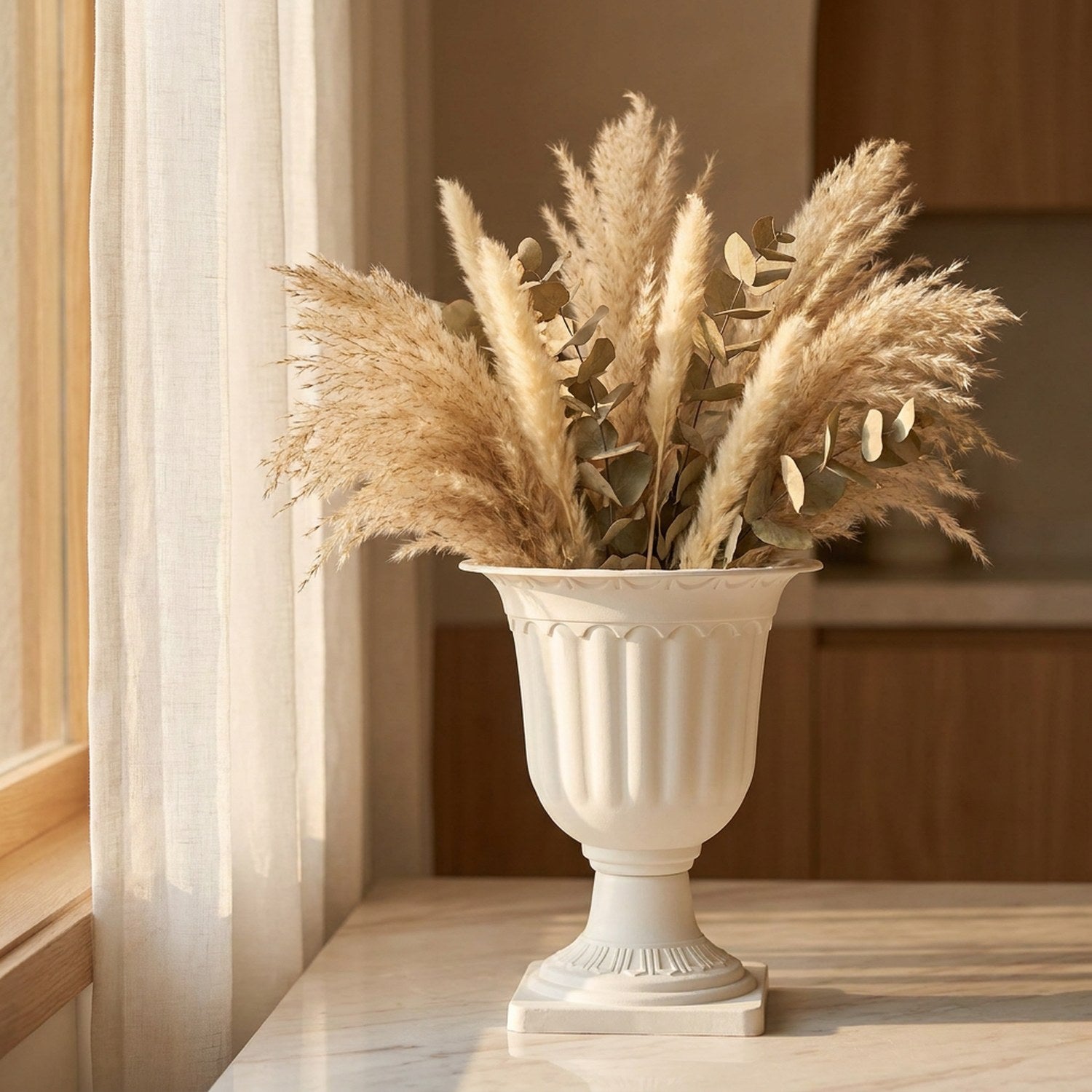Vase médicis blanc garni de pampa séchée posé sur un plan en marbre près d'une fenêtre