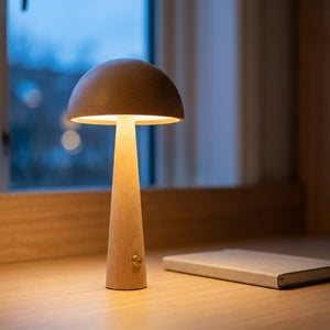 Lampe champignon en bois allumée sur un bureau au crépuscule près d'une fenêtre