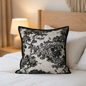 Housse de coussin toile de Jouy posée sur un lit fait contre une tête de lit en bois