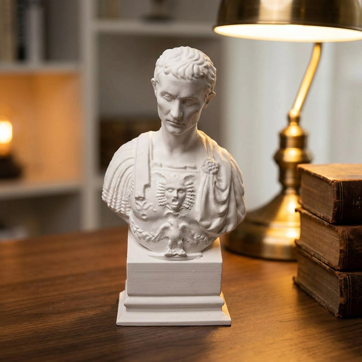 Buste de Jules César en plâtre sur un bureau en bois près d une lampe en laiton