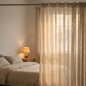 Voilage beige translucide à la fenêtre d'une chambre baignée de lumière douce