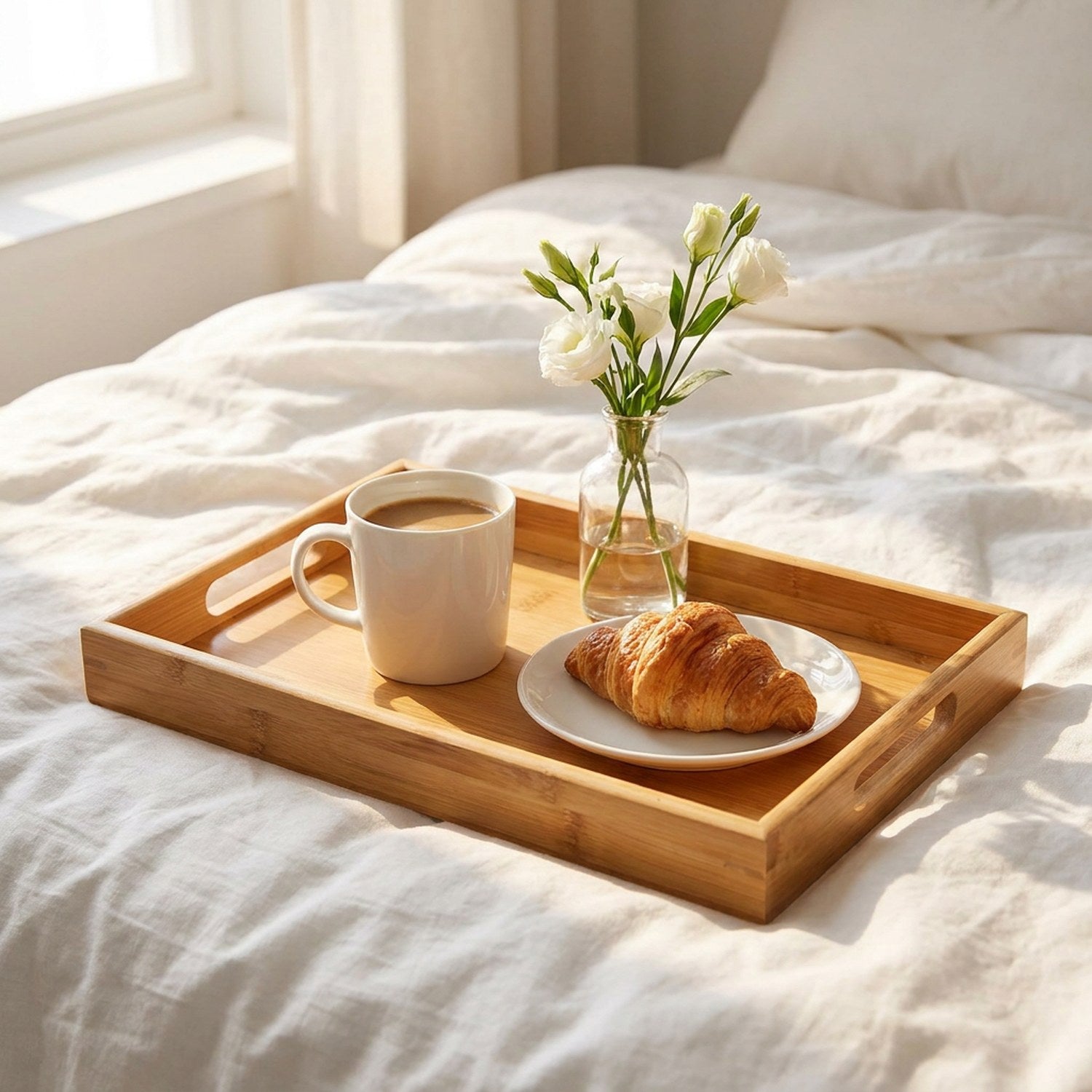 Plateau en bambou sur lit blanc avec petit-déjeuner café croissant et fleurs