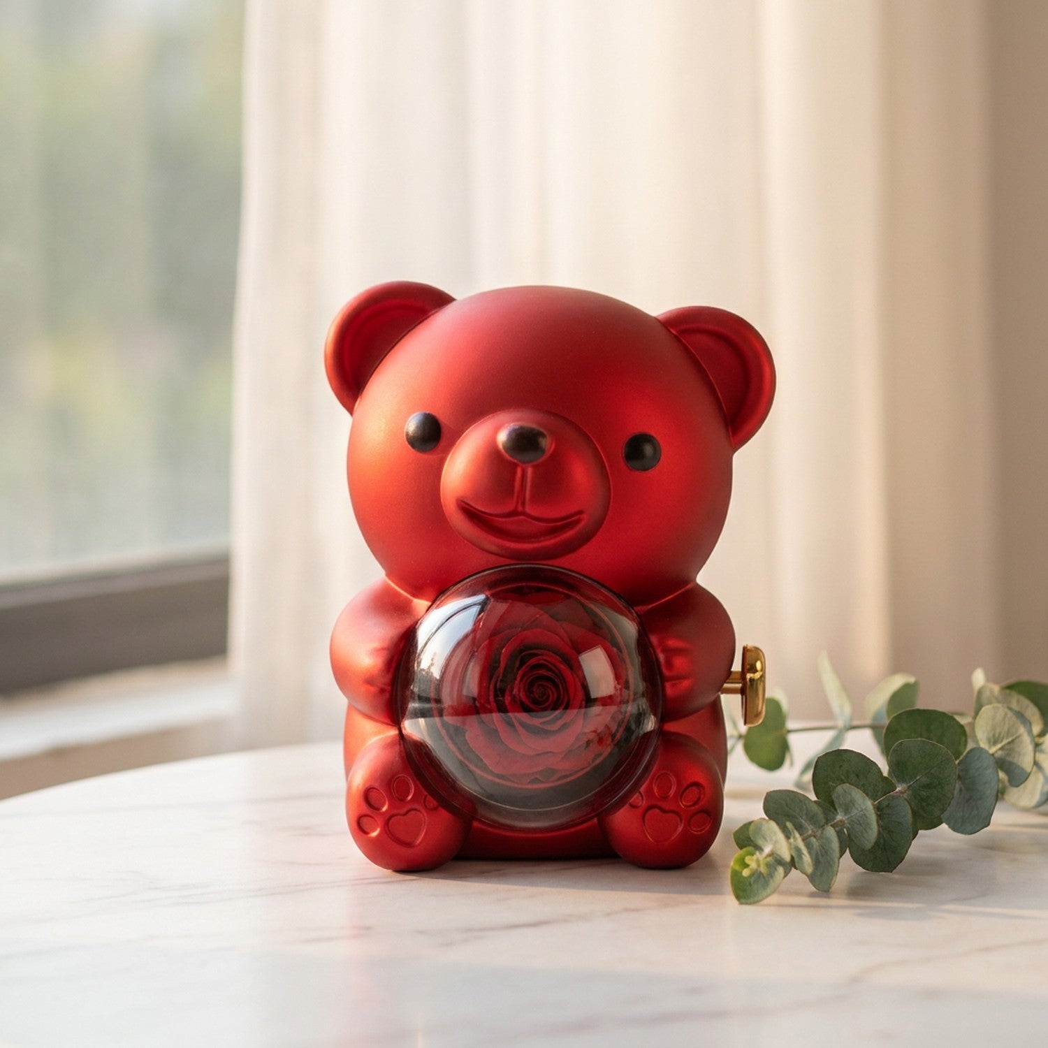 Boîte à bijoux ourson rouge sur une surface en marbre avec brin d'eucalyptus
