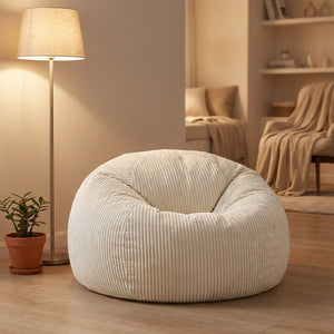Pouf blanc en velours côtelé dans une chambre chaleureuse avec lampadaire