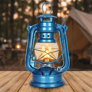 Lanterne à pétrole bleue allumée sur une table en bois en extérieur au crépuscule