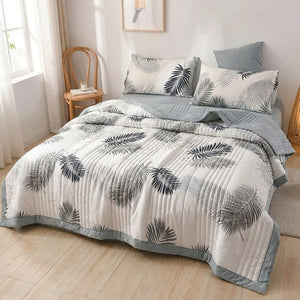 Couette d'été imprimée feuillage sur un lit dans une chambre lumineuse avec chaise en bois