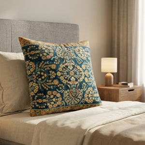 Housse de coussin motif tapis berbère bleu paon calée contre une tête de lit