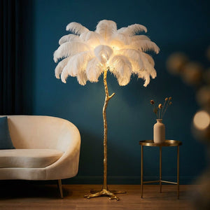 Lampadaire plume d'autruche blanc allumé près d'un canapé sur un mur bleu canard