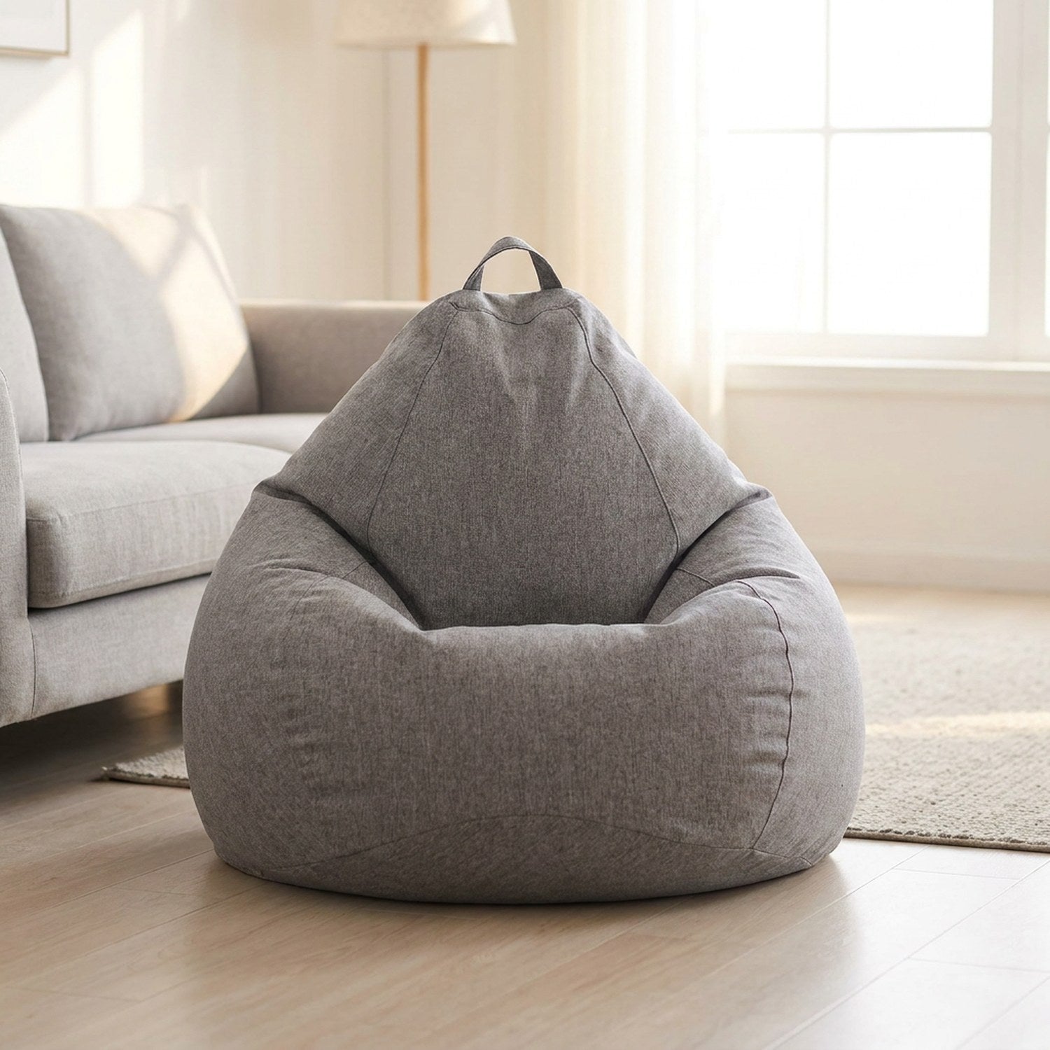 Pouf poire gris chiné près d'un canapé dans un salon scandinave lumineux