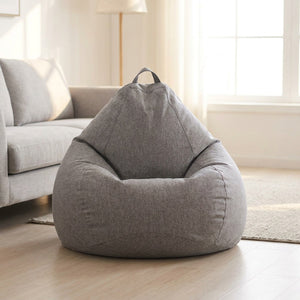 Pouf poire gris chiné près d'un canapé dans un salon scandinave lumineux