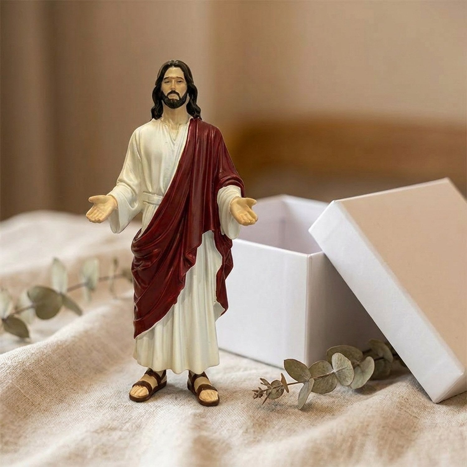 Statue de Jésus-Christ présentée près de son coffret cadeau sur du lin