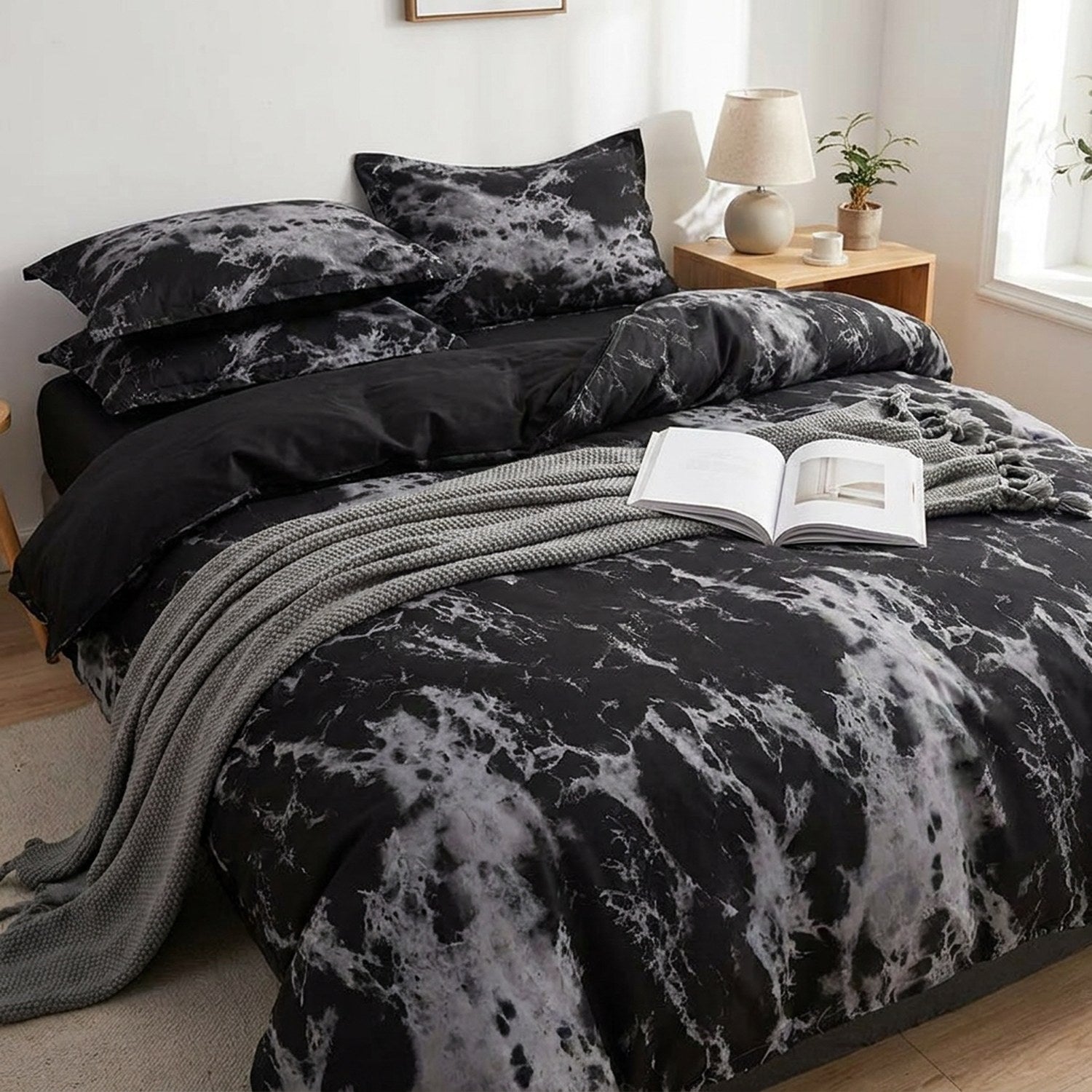 Parure de lit effet marbre noir sur un lit cocooning avec un plaid gris