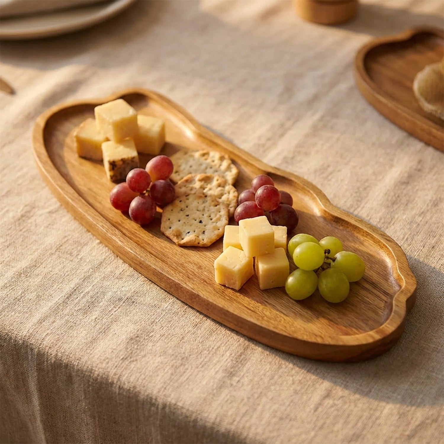 Plateau en bois présentant fromages crackers et raisin pour l'apéritif
