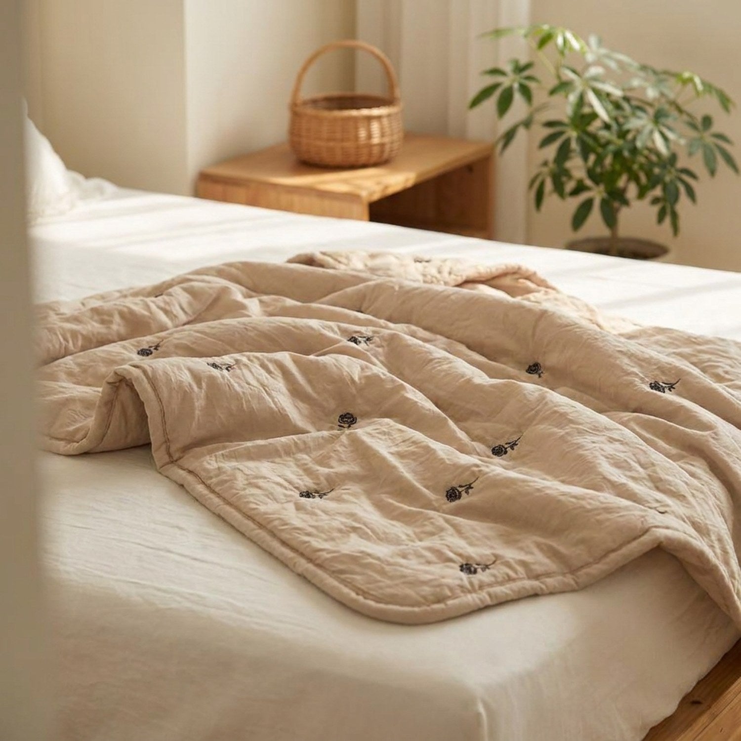 Couette d'été beige pliée sur un lit dans une chambre minimaliste avec plante verte