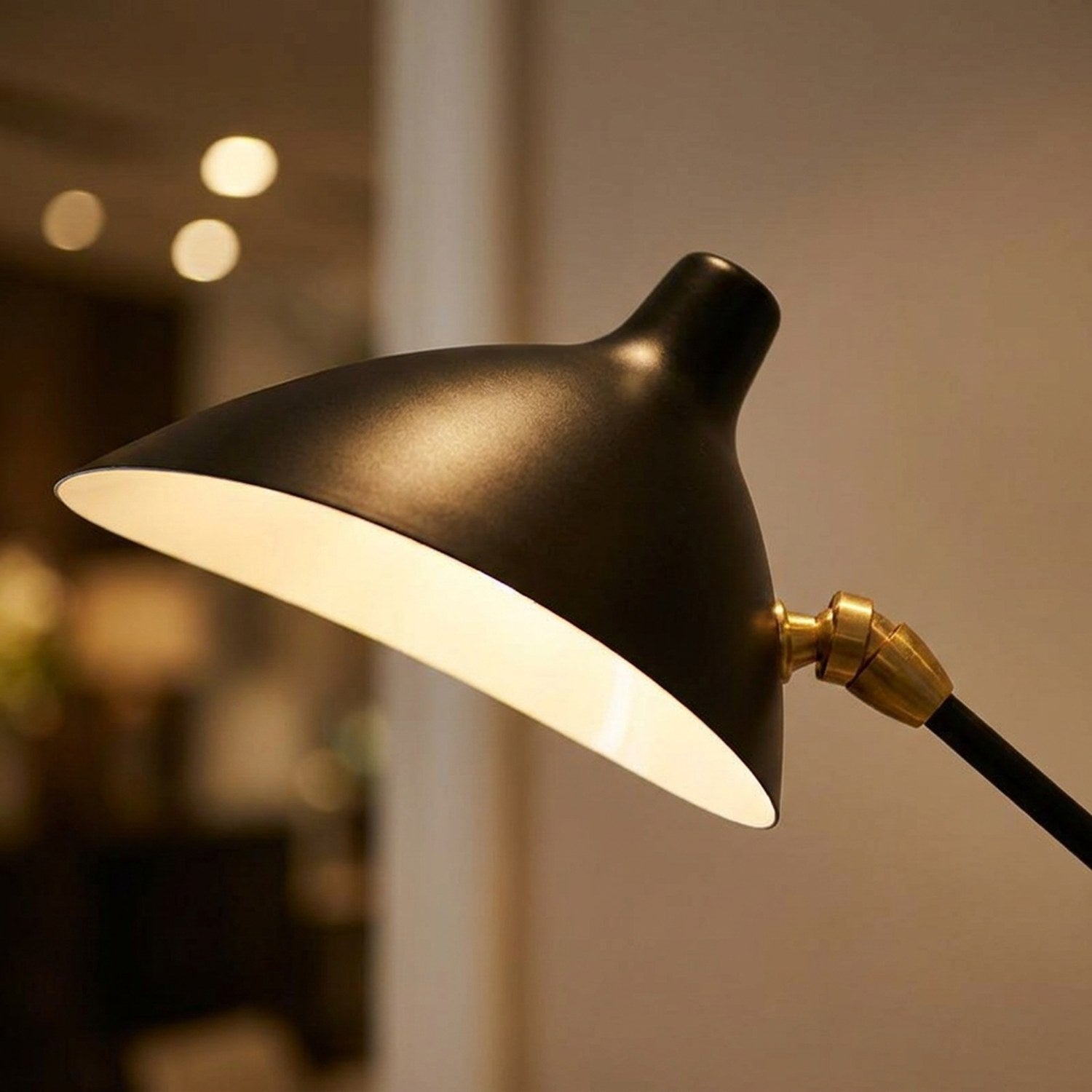Gros plan sur l'abat-jour noir incurvé et la jonction en laiton du lampadaire