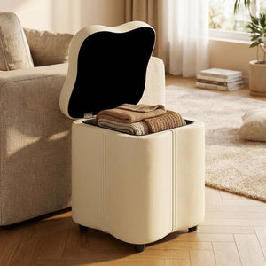 Tabouret coffre crème au couvercle ouvert révélant des plaids rangés à l intérieur près d un canapé