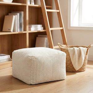 Tabouret pouf blanc près d'une bibliothèque dans un coin lecture