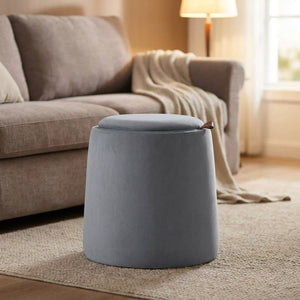 Pouf coffre de rangement gris devant un canapé avec plaid et lampadaire