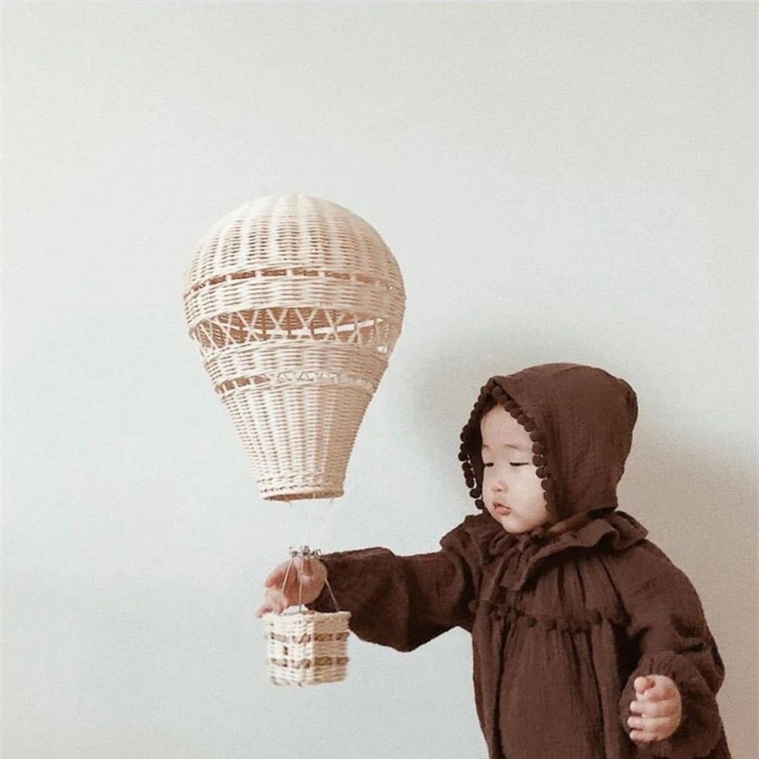 Lustre ballon rotin dans une chambre bébé avec enfant endormi ambiance chaleureuse