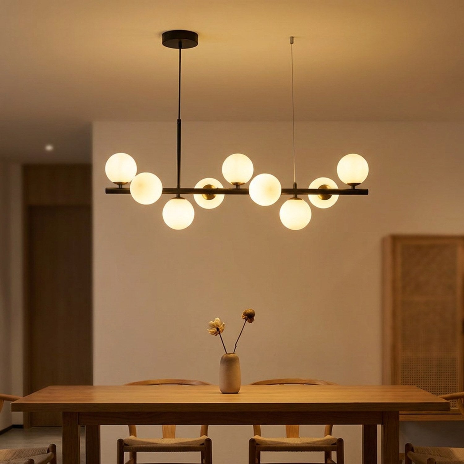 Lustre à boules de verre laiteux au-dessus d'une table en bois le soir