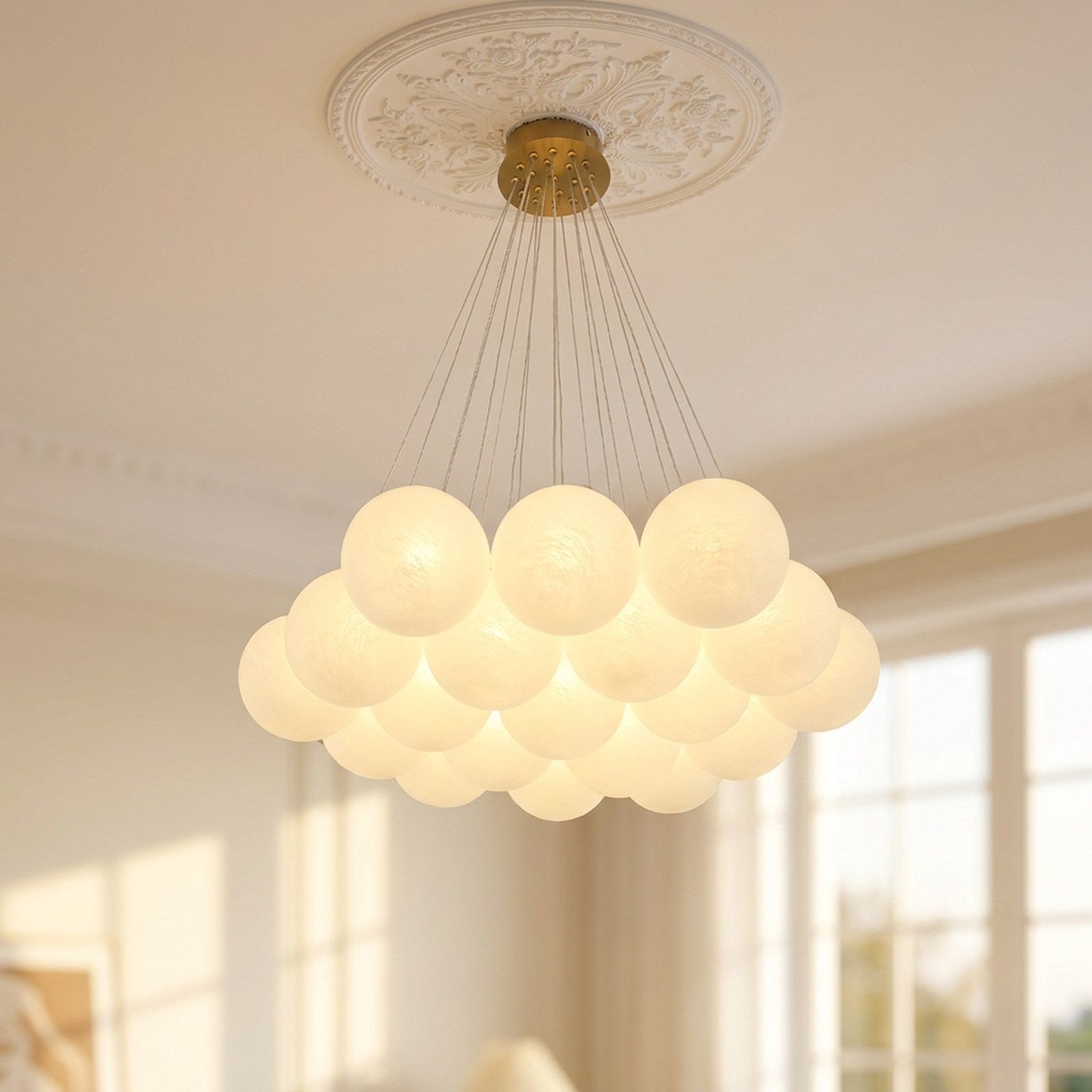 Lustre à boules de verre blanc laiteux avec cadre doré suspendu dans un salon français style haussmannien lampe allumée