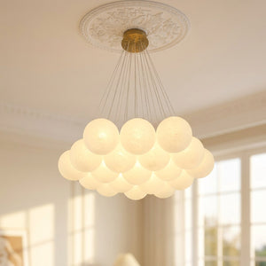 Lustre à boules de verre blanc laiteux avec cadre doré suspendu dans un salon français style haussmannien lampe allumée