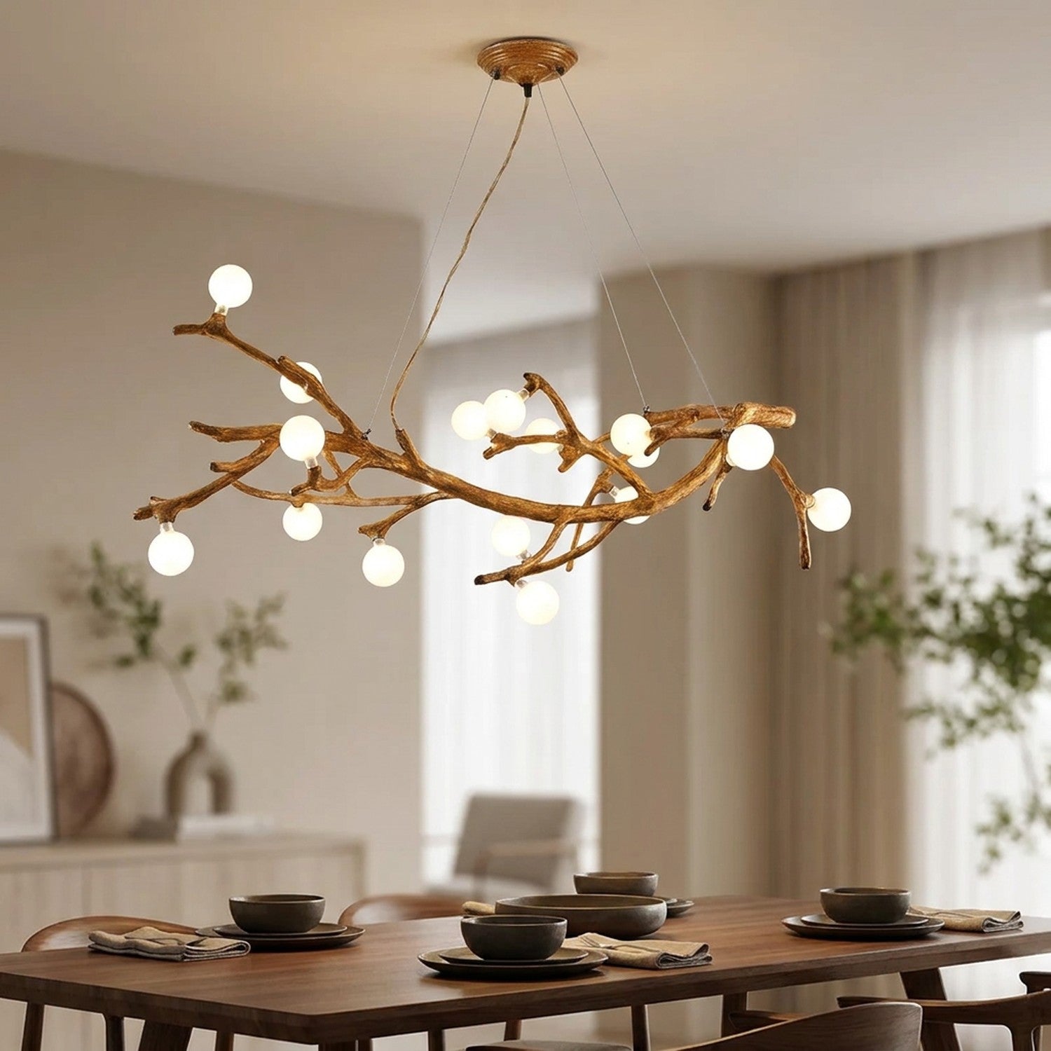 Lustre suspendu en forme de branche d'arbre avec 16 boules en verre givré lumineuses façon lucioles au-dessus d'une table à manger en bois