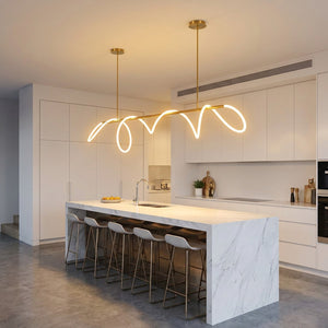 Lustre LED barre linéaire dorée dans une cuisine blanche avec îlot et tabourets
