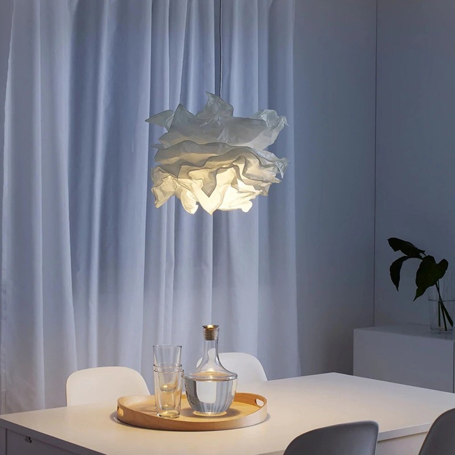 Lustre nuage papier blanc suspendu au-dessus d'une table à manger avec verres et couverts