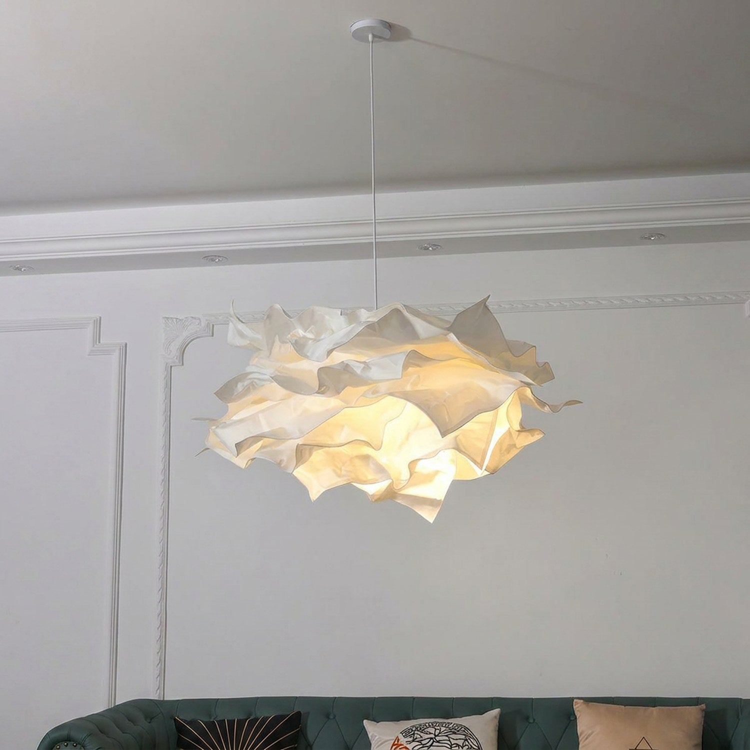 Lustre nuage papier blanc allumé dans un salon haussmannien au-dessus d'un canapé velours