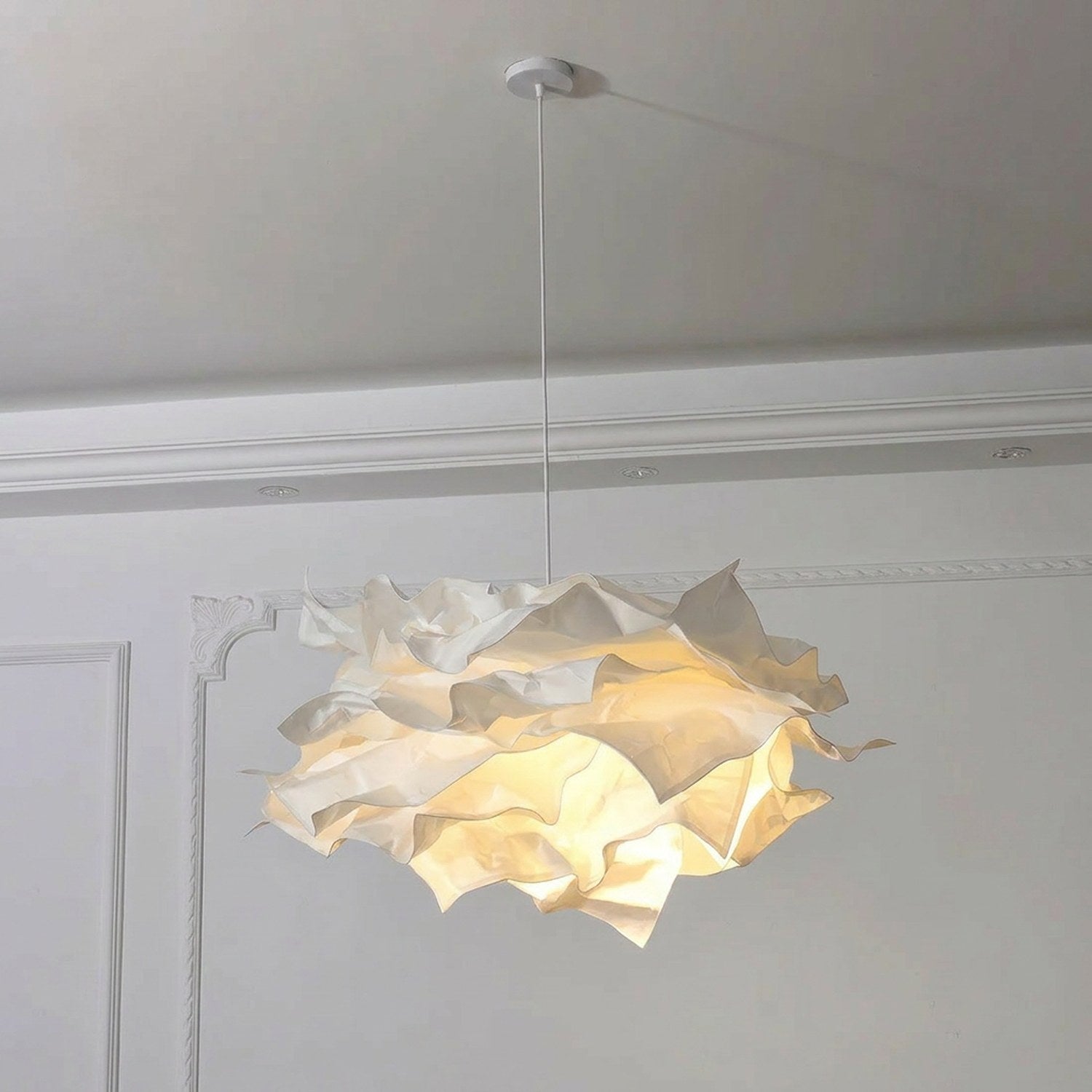 Lustre nuage papier DIY blanc allumé vu de bas dans un intérieur blanc avec moulures élégantes