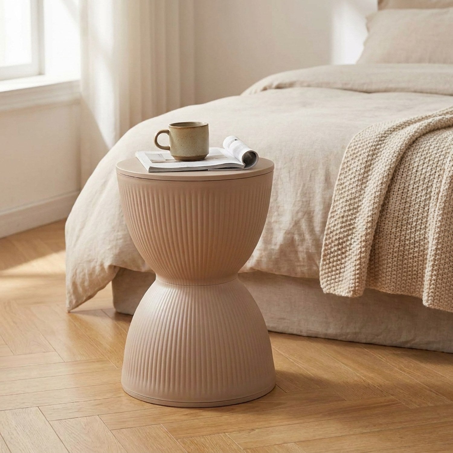 Tabouret rond nordique beige posé au pied d'un lit dans une chambre chaleureuse