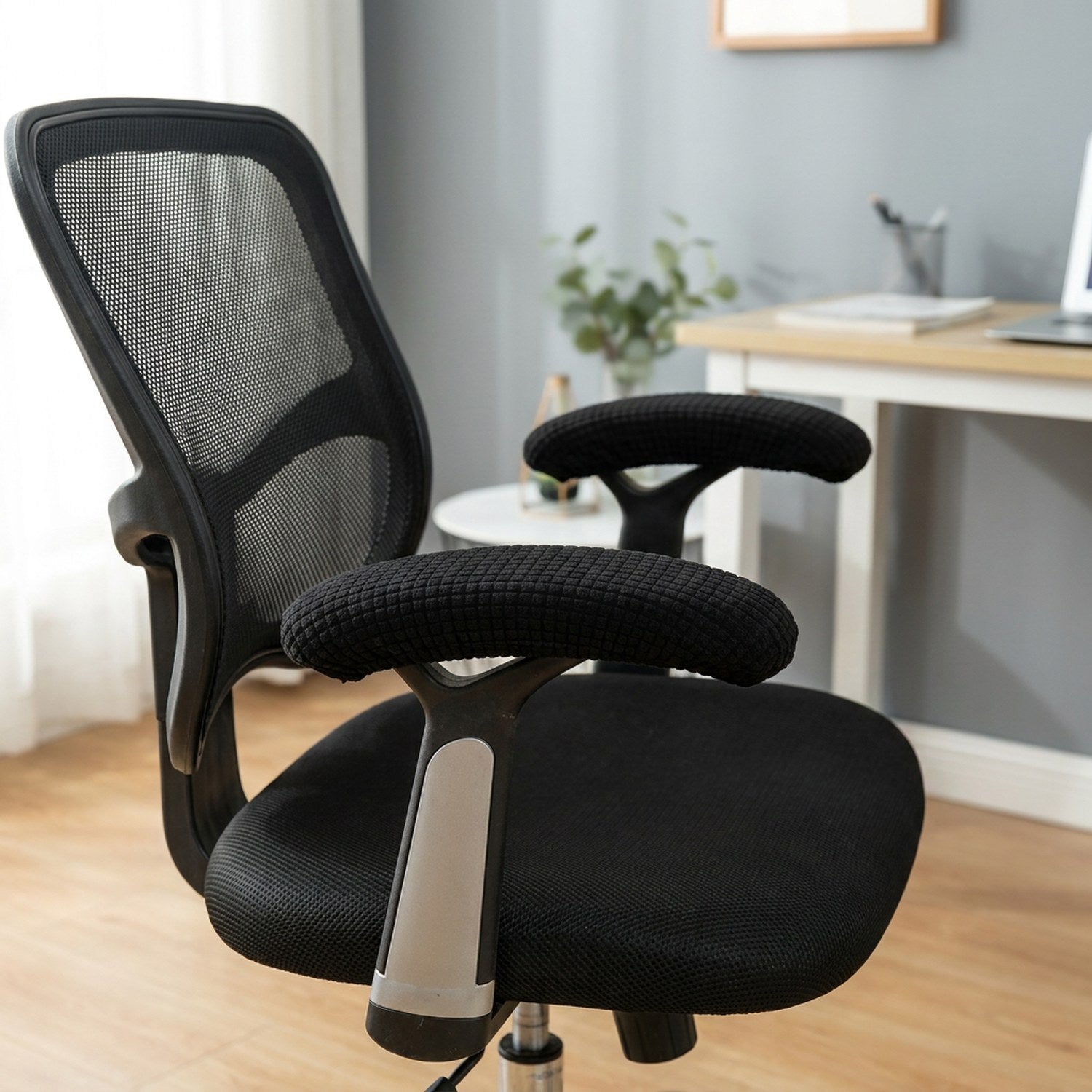 Paire de housses d'accoudoir noires en tissu texturé installées sur les accoudoirs d'une chaise de bureau