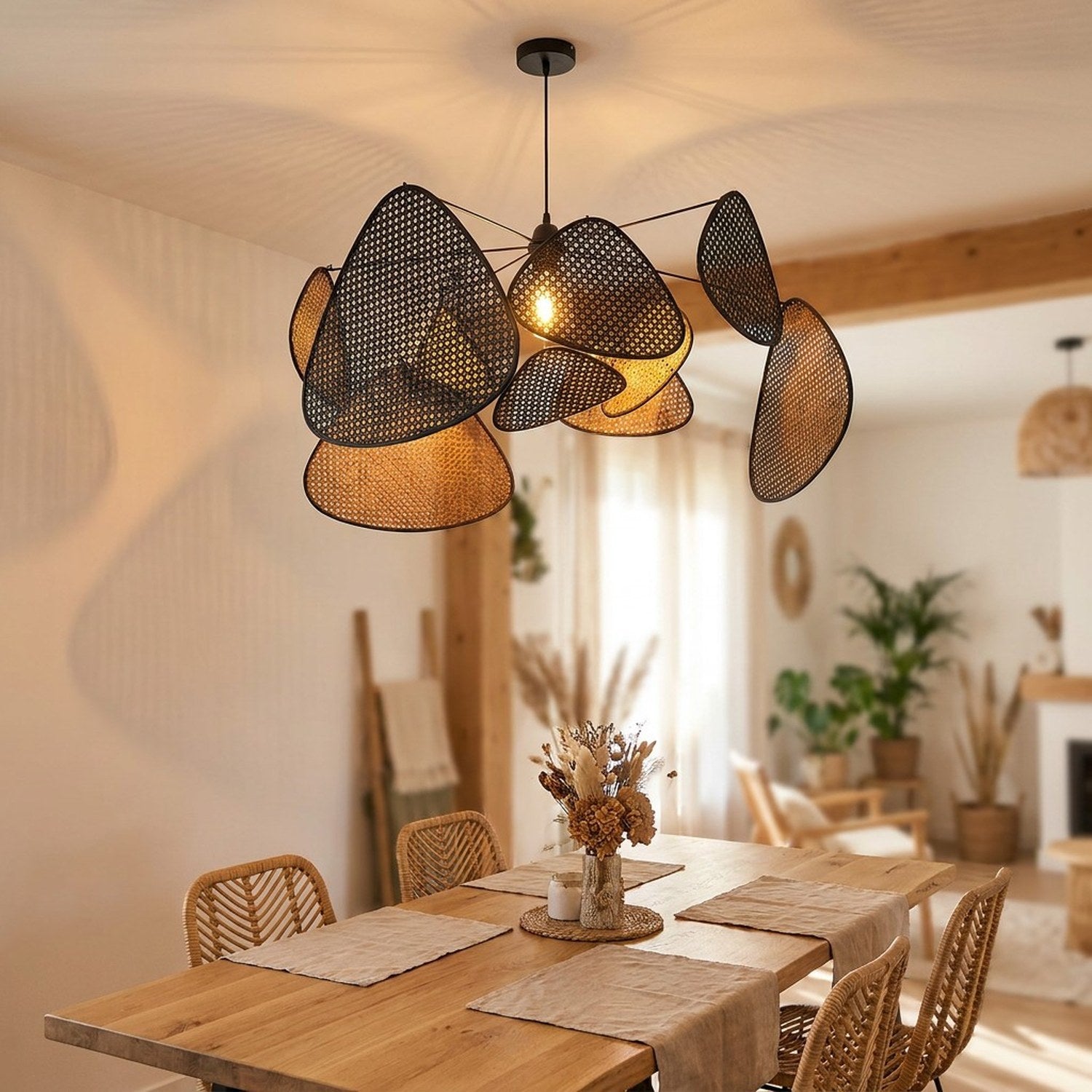 Lustre suspension en rotin à pétales tressés noir allumé dans un salon bohème style wabi-sabi