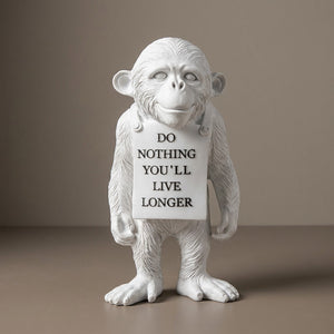 Statuette singe décoratif en résine blanche avec panneau message sur fond taupe