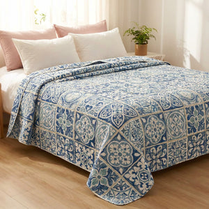 Couvre-lit matelassé motif mosaïque bleue posé sur un lit dans une chambre lumineuse et chaleureuse