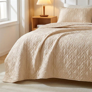Couvre-lit matelassé beige au motif losange posé sur un lit dans une chambre lumineuse