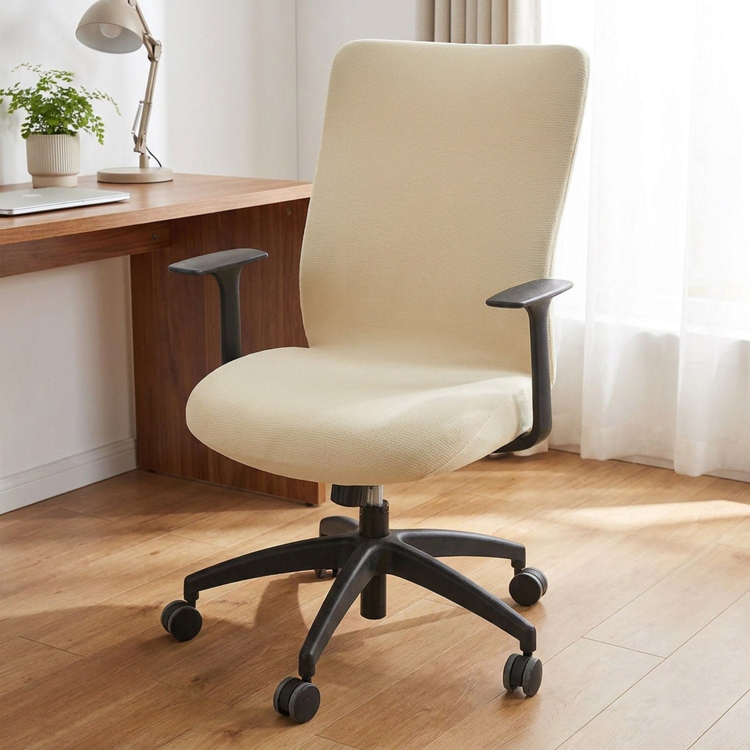 Housse de chaise de bureau beige installée sur un fauteuil pivotant devant un bureau en bois