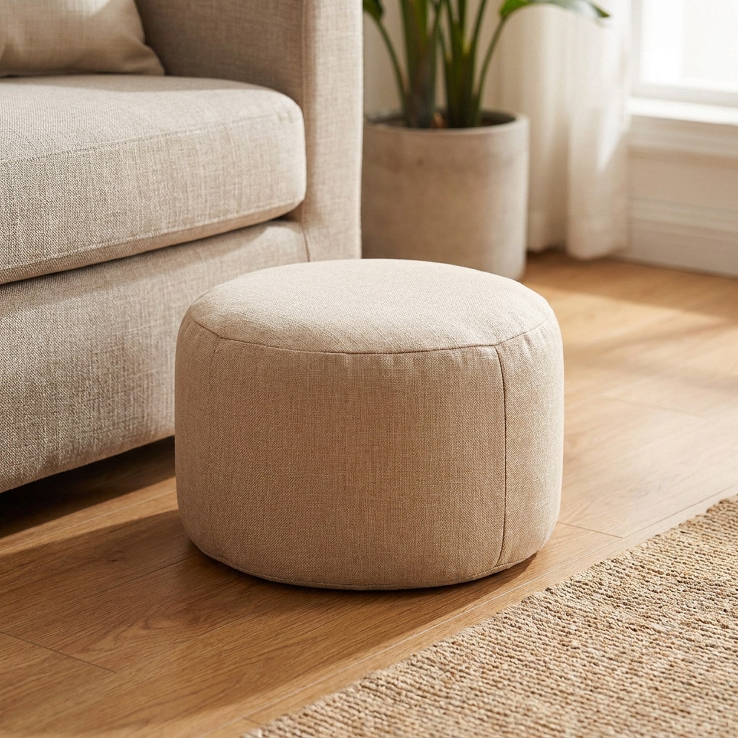 Pouf tabouret rond en lin beige posé au sol dans un salon lumineux près d'un fauteuil